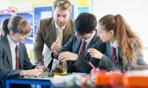 Teacher guiding students assembling robot in science class