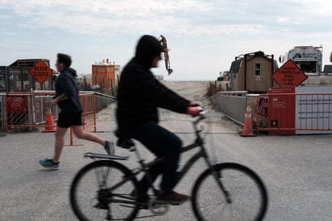 man cycles past construction equipment on the beach