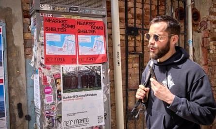 A man walks past posters for the Ukrainian pavilion showing maps of the nearest bomb shelter.