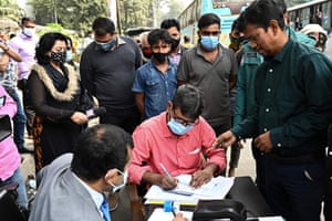Dhaka, Bangladesh: a commuter pays a fine to a magistrate at a mobile court after being stopped and charged by police while outdoors without a face mask