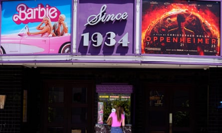 A patron buys a movie ticket underneath a marquee featuring the films Barbie and Oppenheimer at the Los Feliz Theatre in Los Angeles.