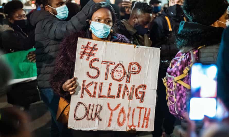 一名妇女举着牌子，烛光游行中的示威者记得那些被尼日利亚警察殴打的人