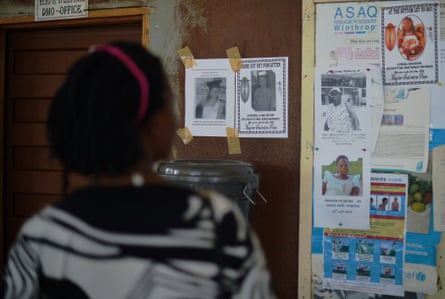 A woman looks at the obituary notices for medical staff who have died from the Ebola virus