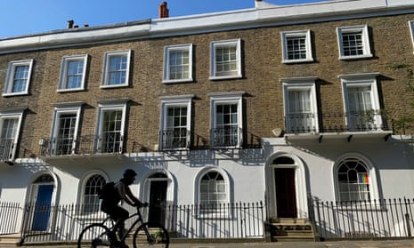 A cyclist rides past houses on a street in Islington, London