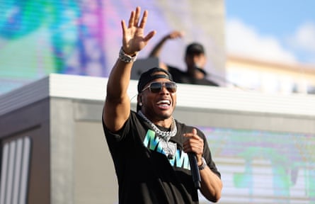 Nelly holds a microphone while waving