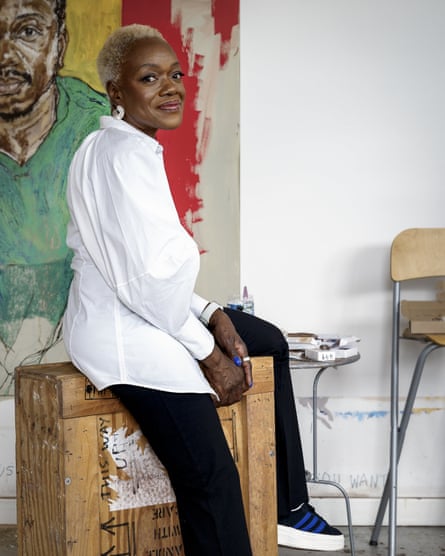 Claudette Johnson wearing white top and black trousers sitting on crate with painting in background