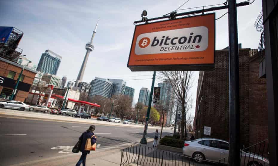 People walk by a ‘Bitcoin Decentral’ sign for a co-working space in Toronto
