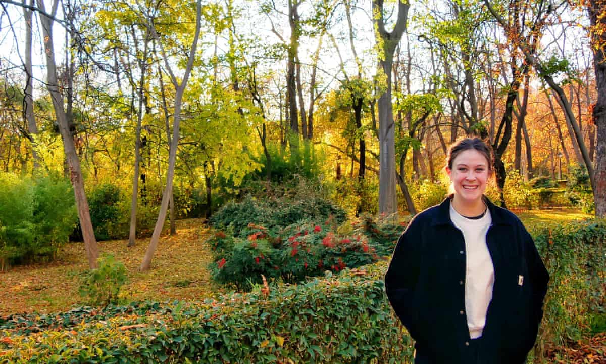 Anna Beddow stands in the autumny park, smiling.