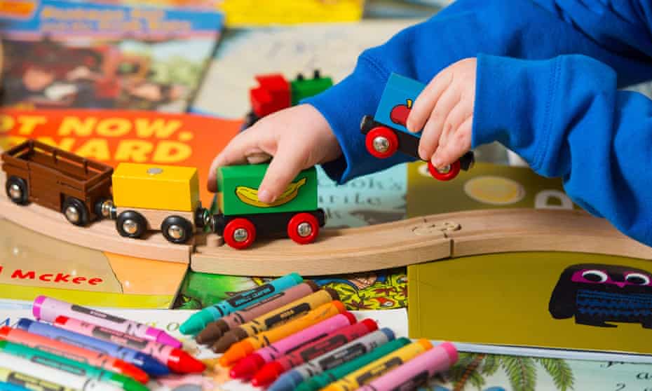 A child playing with a train set and crayons