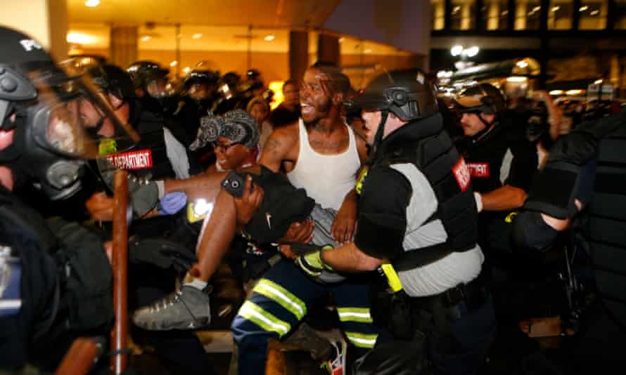 Police and protesters carry a seriously wounded protester into the parking area of the the Omni Hotel during a march to protest the death of Keith Scott.