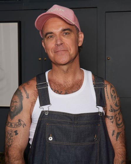 Robbie Williams wearing a pink cap and dungarees