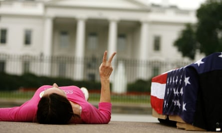 An anti-war protester lays next to a flag-draped mock casket outside the White House in 2016.