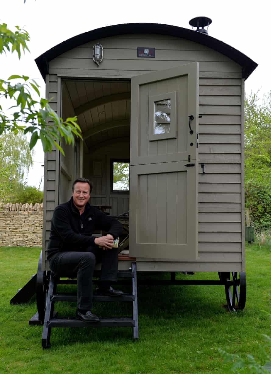 David Cameron sitting on the steps of a luxury cabin he installed in his Cotswolds garden.