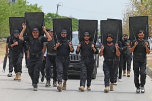 Islamabad, Pakistan. Security personnel with ballistic shields escort a vehicle carrying Imran Khan, the country’s former prime minister, after he appeared before an anti-terrorism court