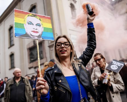 A protester holding an anti-Orbán placard and a smoke canister.