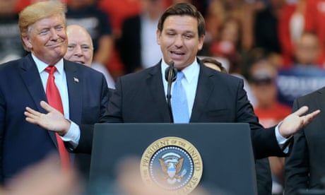 Donald Trump looks on as Ron DeSantis speaks.