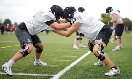 Two offensive linemen go up against each other wearing padding on top of their helmets for safety during a training session for the NFL Academy at Loughborough University.