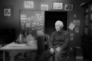 Masaharu sits in his living room surrounded by photos of his wife Kimiko and carers