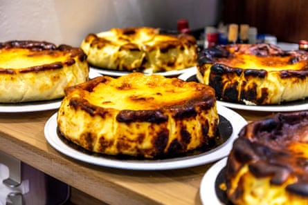 Five large, baked cheesecakes on a table; they have blackened edges