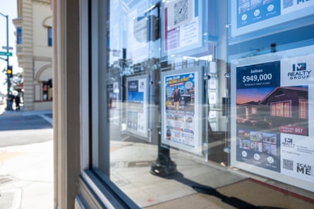 Homes listed for sale in the window of a real estate office.