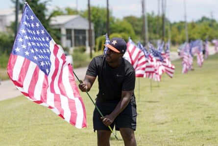 Bryan Smart plants American flags along Hillcroft Avenue as he walks toward The Fountain of Praise church on Sunday in Houston. A public memorial and private funeral service for George Floyd will be held at the church.