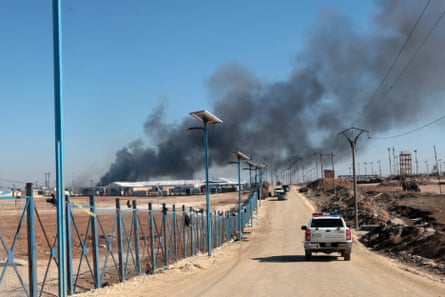 thick black smoke is billowing into the blue sky from the camp’s low-rise buildings.