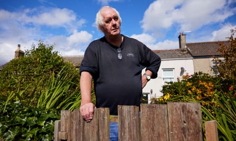 Raymond Dixon leans on a wooden fence outside his house