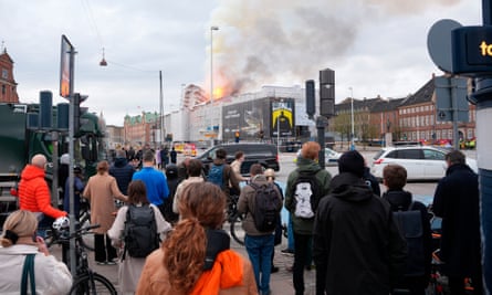 People stand in the street looking towards the fire at the old stock exchange in Copenhagen