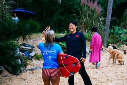 Jingwei Wang high fives a surfer on the beach at the QS Wanning International on Hainan Island, China
