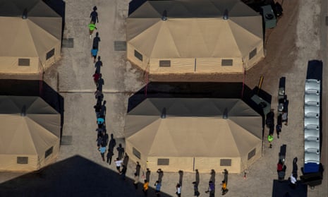 Migrant children are led by staff in single file between tents at a detention facility next to the Mexican border in Tornillo, Texas, in June 2018.