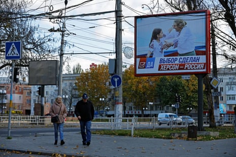 People walk along a street in Kherson in Octobernext to a banner reading "The choice is made. Kherson is Russia".