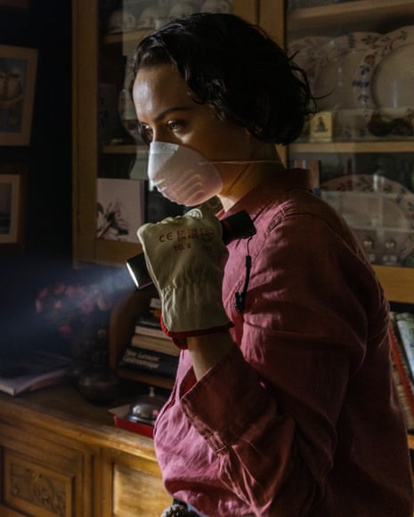 woman wearing mask and gloves holds up flashlight