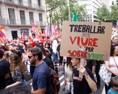A man holds a banner reading 'Work to Live not to Survive' as demonstrators attend a rally to mark the International Workers' Day in Barcelona, Spain.