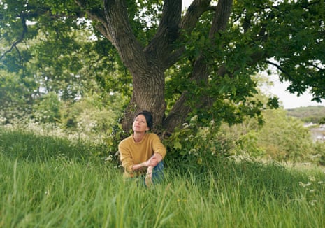 Natalie Fée sitting in the grass next to an oak tree