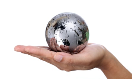 Hand holding metal puzzle globe on white background