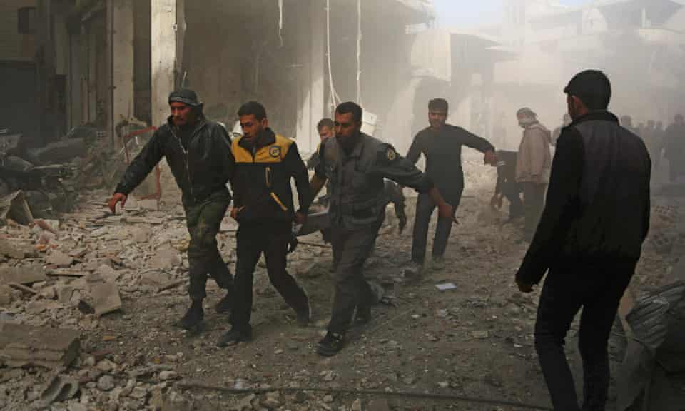 Volunteers from the Syria Civil Defence, known as the White Helmets, carry a victim following a reported air strike in the rebel-controlled town of Hamouria.
