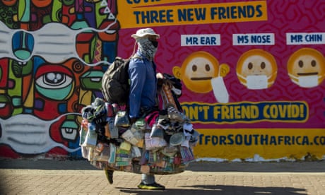 A street vendor walks past a mural on how to
prevent the spread of coronavirus in Soweto, South
Africa