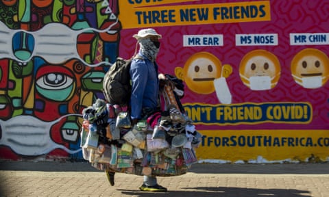 A street vendor walks past a mural on how to prevent the spread of coronavirus in Soweto, South Africa