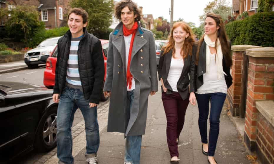 Mixed sex group of teenagers walking along the street in an urban area