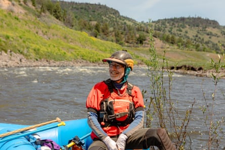 a man smiles while sitting in a small raft on a river