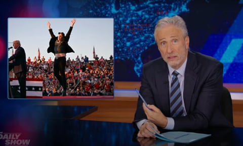 man in suit in front of picture of a man jumping at a rally