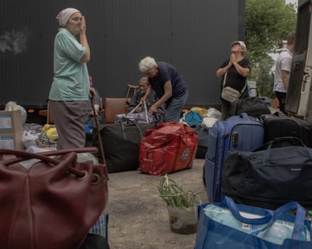 Older evacuees pray and cry, surrounded by bags and suitcases.