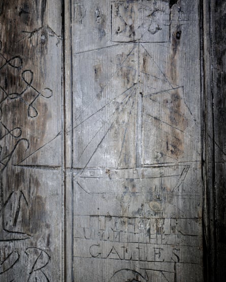 Ship with large masts etched on to a wooden door with illegible text underneath