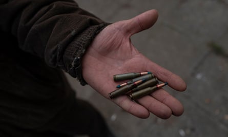A resident picks up some of the bullets that scatter the ground near a former Russian military position 