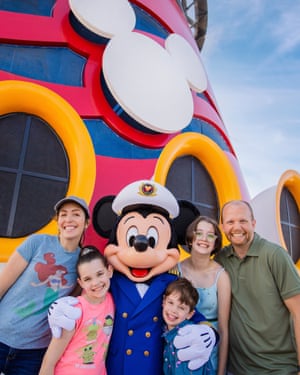 A mother, father and their three children posing with a Mickey Mouse performer.