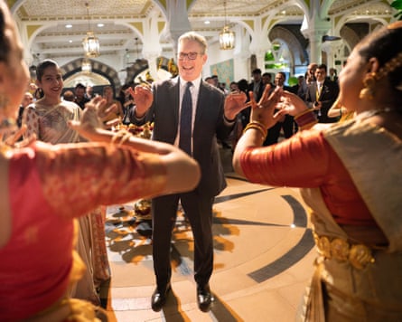 Keir Starmer laughs as he pretends to conduct a group in Indian musicians and dancers