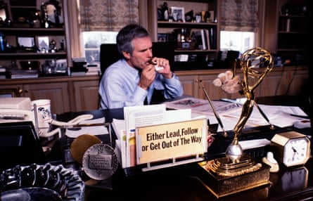 A man lights a cigar in his office