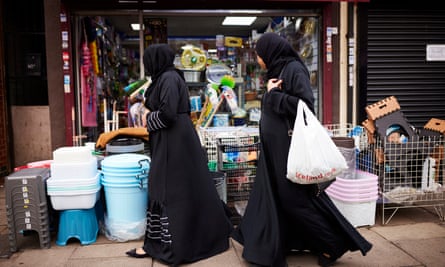 Two women wearing hijab walk in front of a discount shop in Green Lane Road, Leicester.