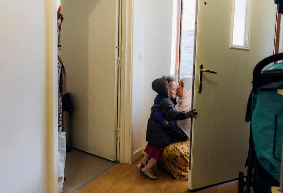 Shukri Adan kneels to hug her daughter as she tries to follow her out of the door
