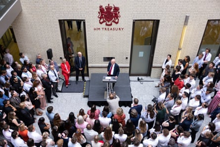 John Healey at podium surrounded by Treasury staff.